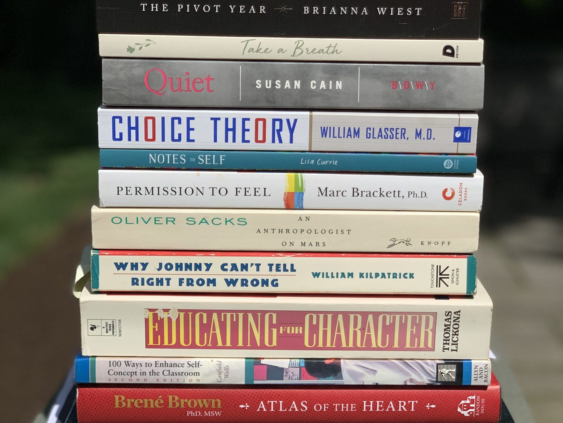 A stack of books on psychology, education, and emotional intelligence, including Choice Theory by William Glasser and works by Brené Brown and Oliver Sacks